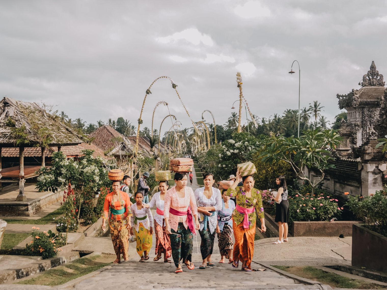 Frauen mit Körben auf Kopf laufen durch Tempelstraße in Bali