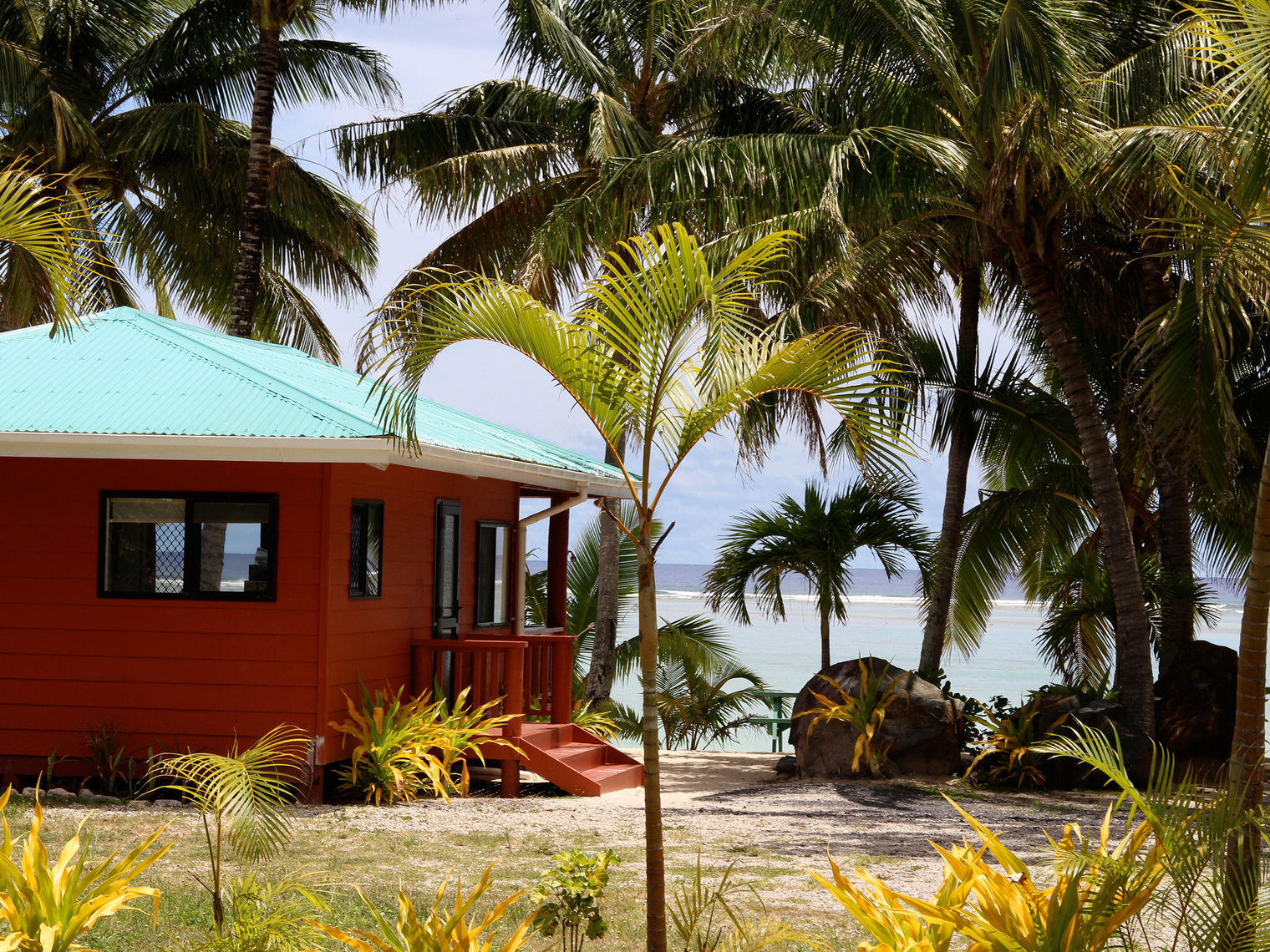 Bella Beach bungalows with ocean in the background in the Cook Islands