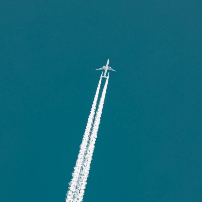 Plane flying through the sky with vapour trails