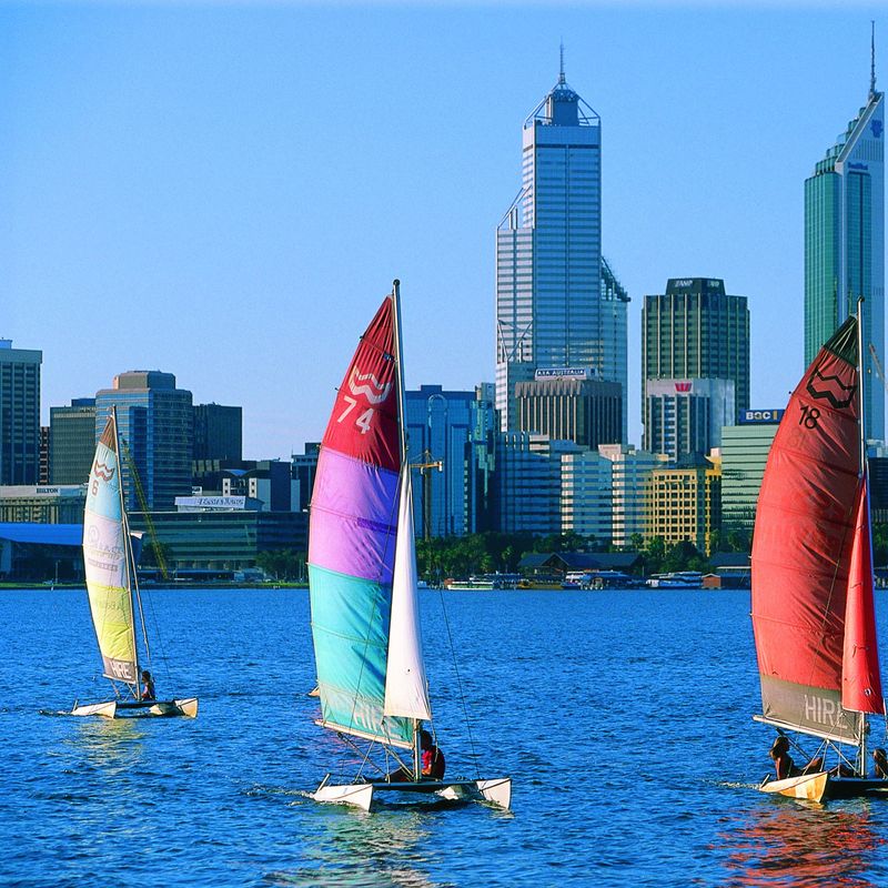 Catamarans met kleurrijke zeilen glijden langs de skyline van de stad in Western Australia, Perth