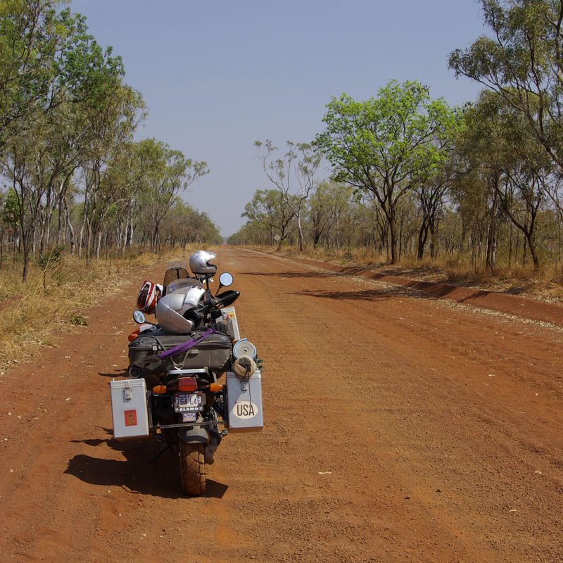 Een bepakte motor op een onverharde, rode weg in Australië