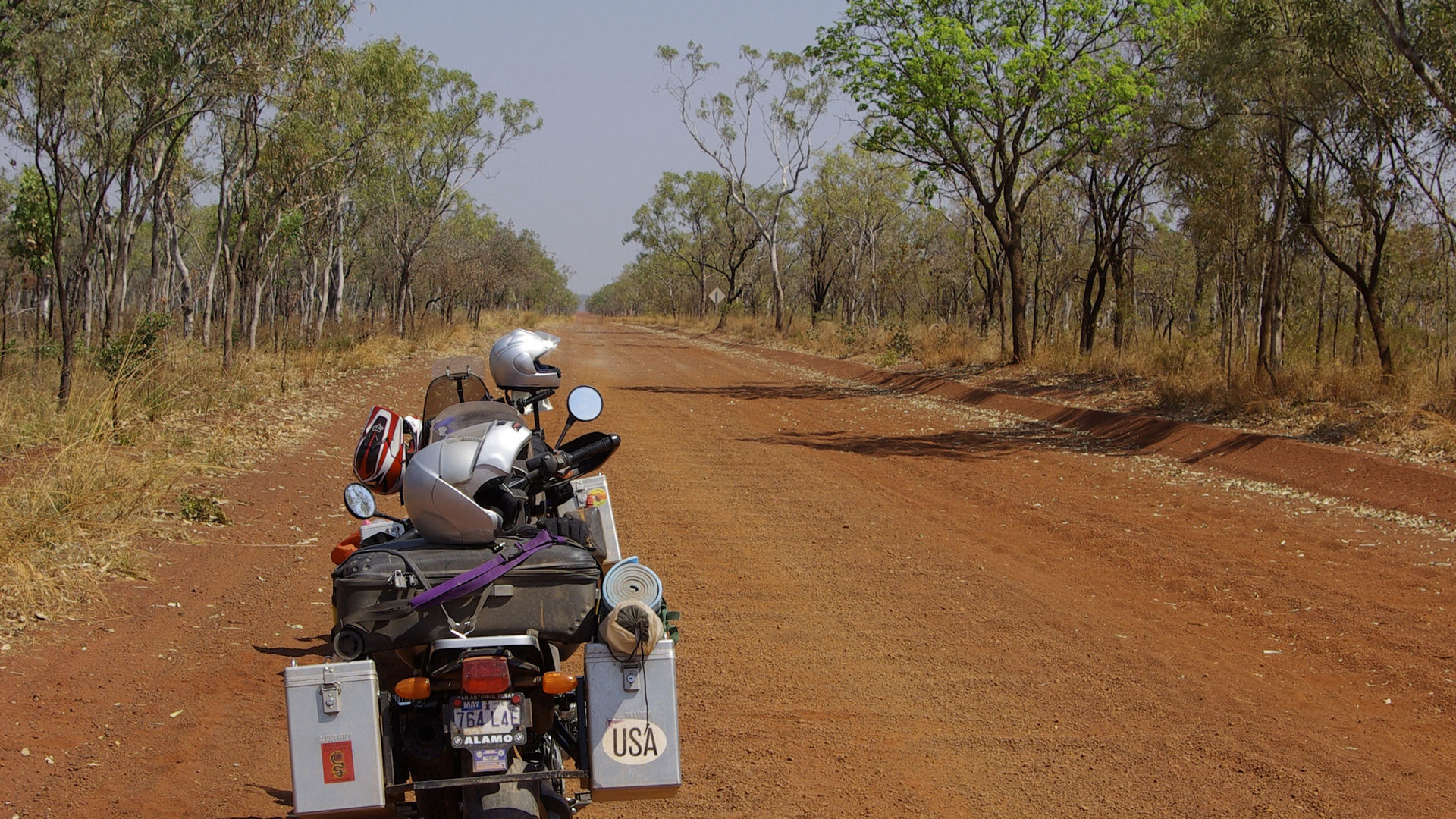 Een bepakte motor op een onverharde, rode weg in Australië