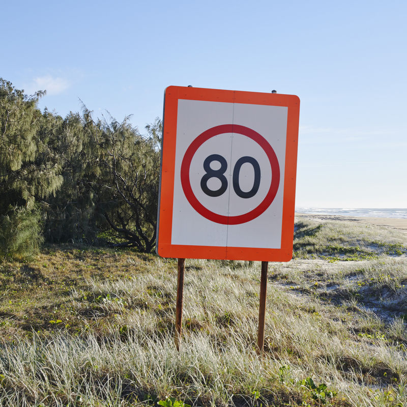 Verkeersbord met maximumsnelheid 80 km/u bij duinen en zee
