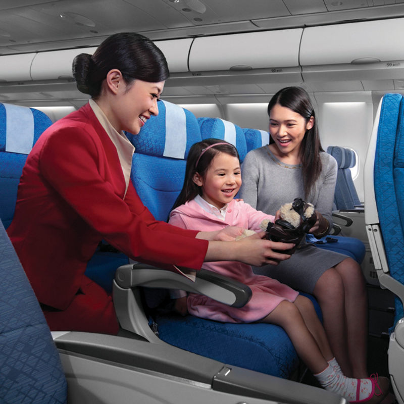 Stewardess geeft een presentje aan een vrouw en een klein meisje in een vliegtuig