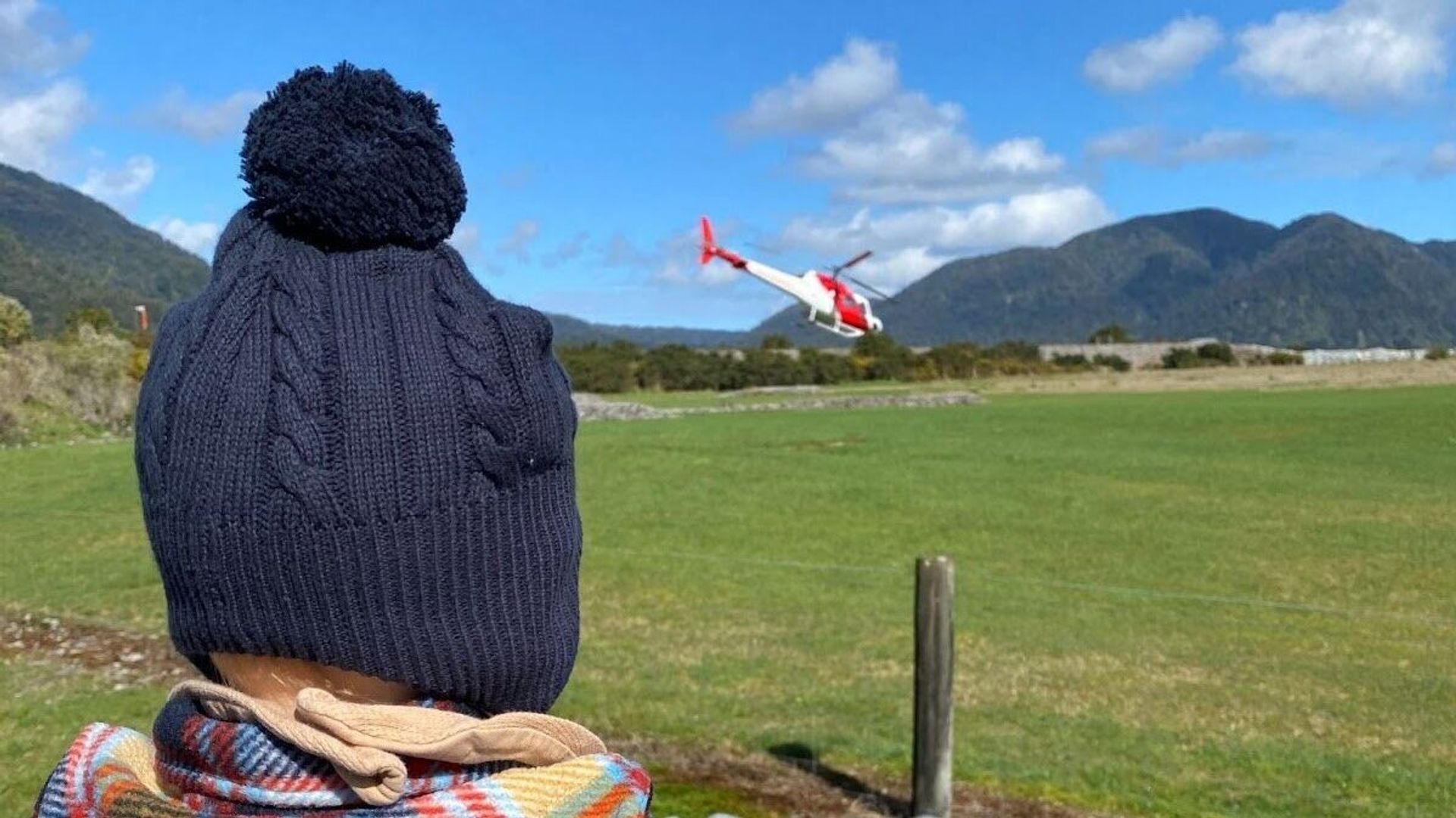 Kind beobachtet einen landenden Hubschrauber in einer Landschaft während einer Familienreise durch Neuseeland
