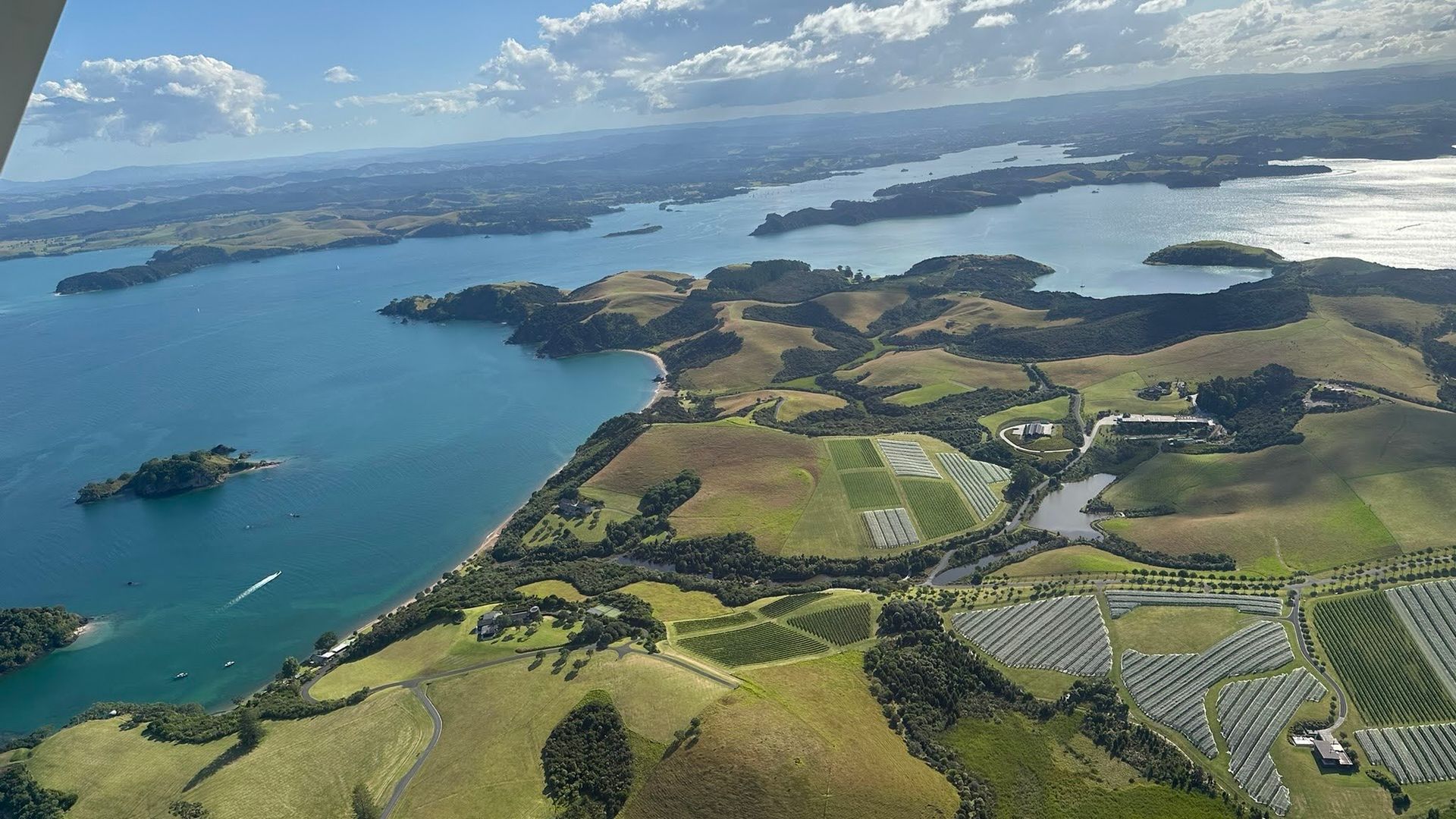 Blick aus dem Fenster eines Kleinflugzeugs auf eine Küstenlandschaft mit Weinbergen in Neuseeland