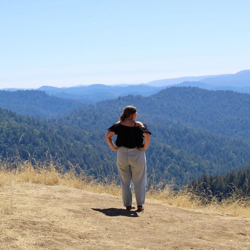 Eine Frau steht an einem Aussichtspunkt mit Blick auf den Redwoods Park, USA