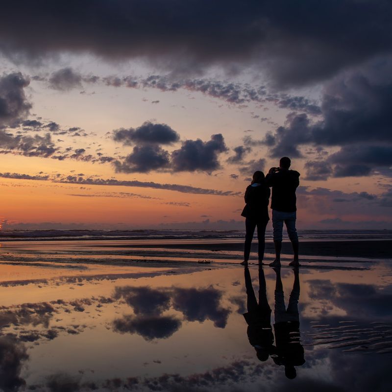 Ein Paar, das den Sonnenuntergang am Cannon Beach in Oregon beobachtet