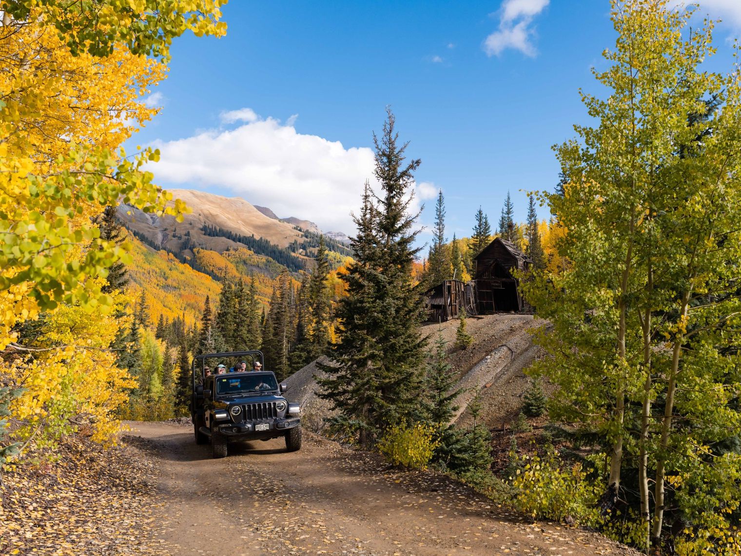 Jeep mit Urlaubern fährt durch die herbstliche Landschaft von Ouray, Colorado