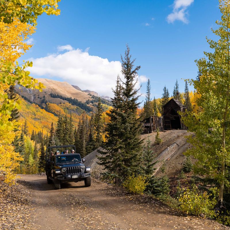 Jeep mit Urlaubern fährt durch die herbstliche Landschaft von Ouray, Colorado