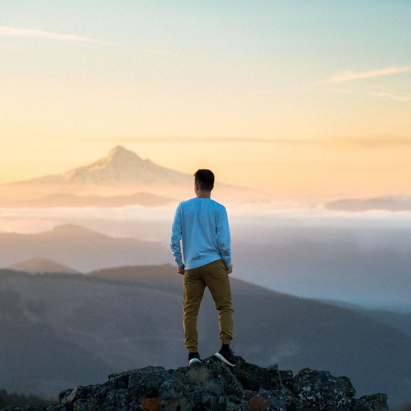 Een man op de top van een berg uitkijkend over een berglandschap