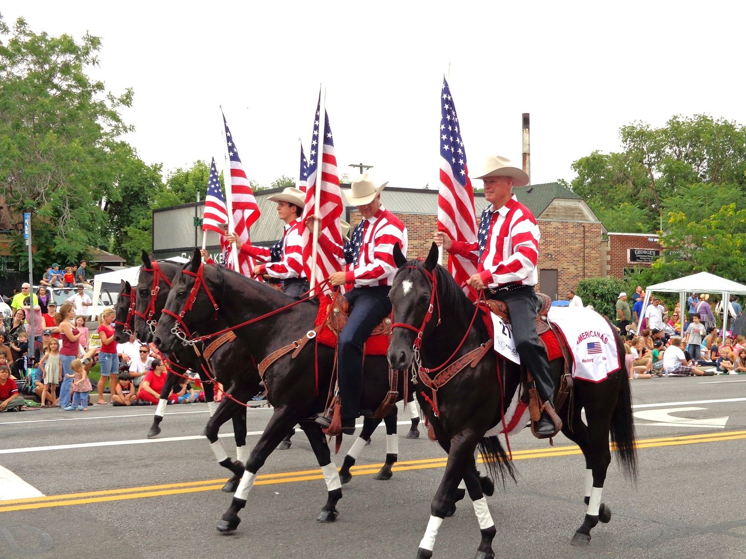 Männer mit amerikanischen Flaggen reiten auf Pferden auf Parade