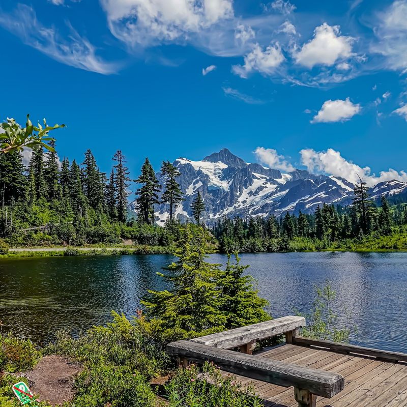 Een vredig meer in het Mount Baker-Snoqualmie National Forest in Washington, met dichte evergreens en besneeuwde bergtoppen op de achtergrond.