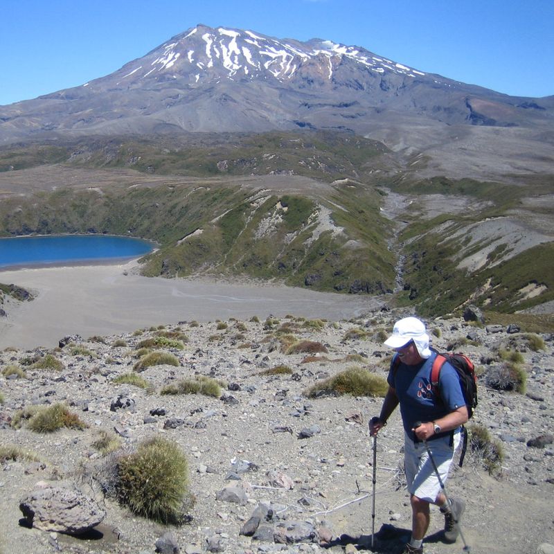 Wandelaar op de Tongariro Alpine Crossing met een blauw kratermeer en Mount Ngauruhoe op de achtergrond, Nieuw-Zeeland