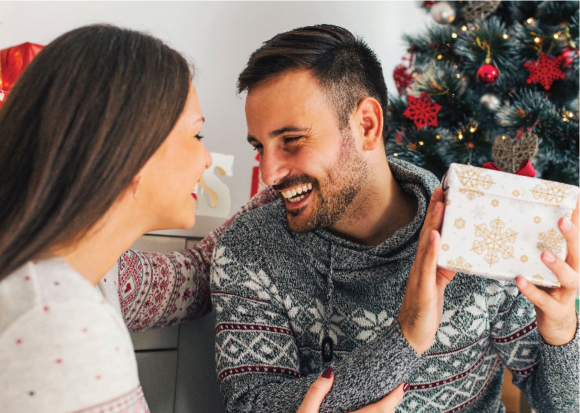 A man and woman looking at a Christmas gift.