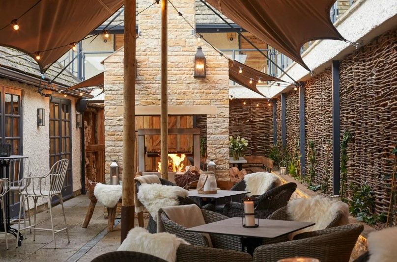 A patio with tables and chairs and a fireplace.