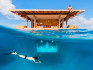 A man and woman are swimming in the ocean under a house.