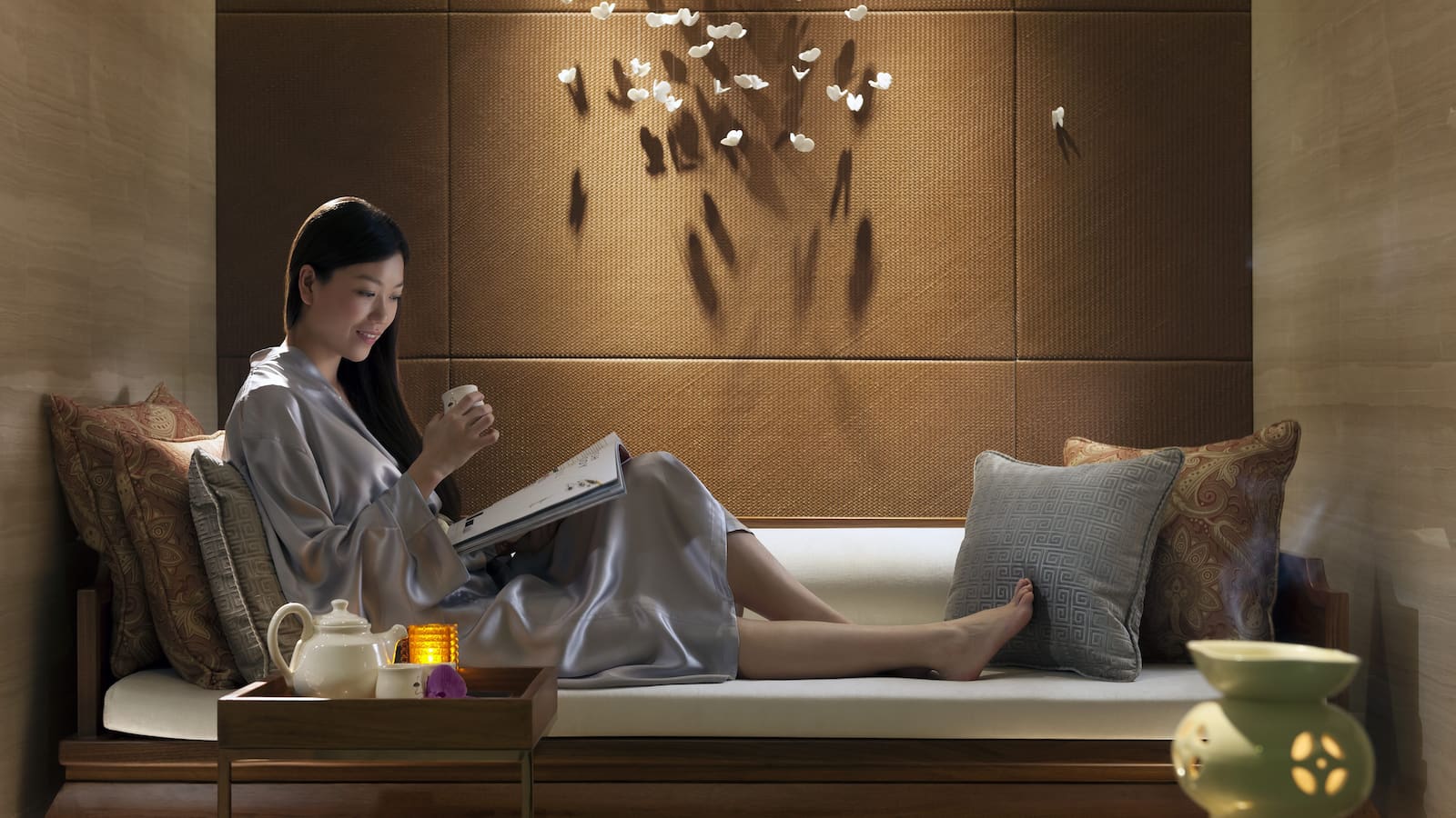 A woman is sitting on a bed reading a book.