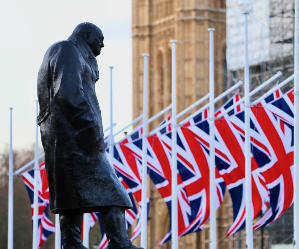 A statue of Winston Churchill in front of British flags.