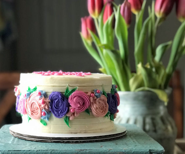 A pink and purple cake sitting on a table next to tulips.