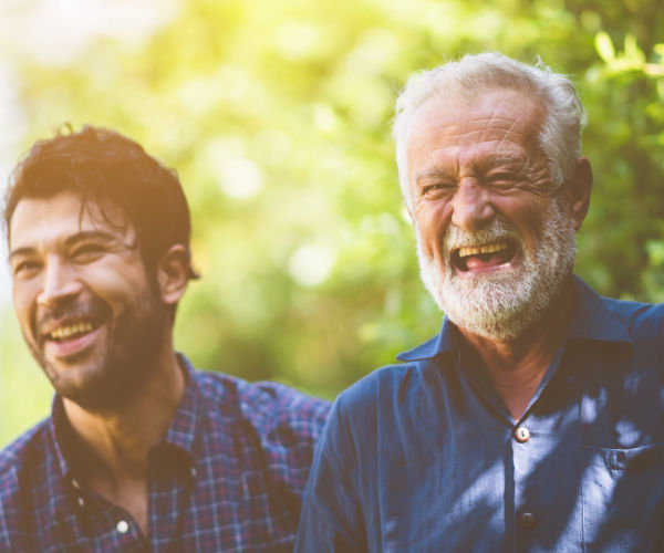 Two older men laughing in a park.