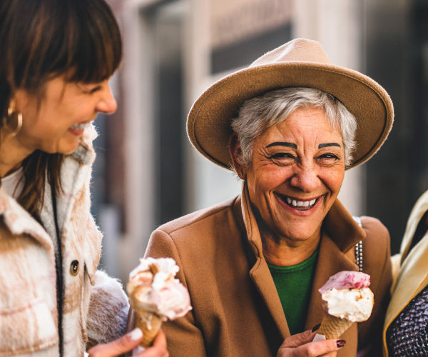 Three older women laughing while eating ice cream cones.
