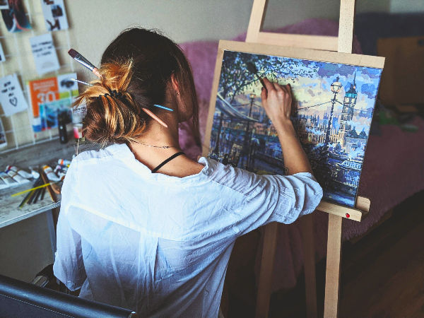 A woman is painting on an easel in her home.