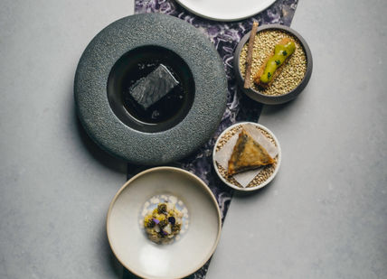 An image of a table with plates and bowls, Nine-course tasting menu at the Chef’s Table. Amethyst