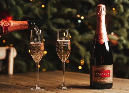 An image of a bottle of champagne being poured into a glass, Wine and Dine Experience. Balfour Winery