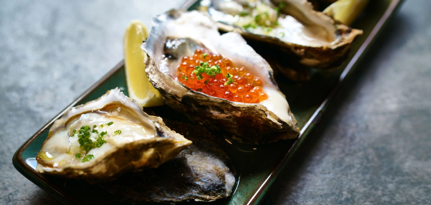 Oysters with caviar and lemon wedges on a plate.