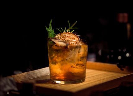 An image of a drink on a wooden board, Group cocktail making experience. Black Parrot