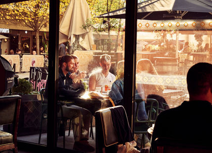 An image of people sitting in a table outside. The Botanist Broadgate Circle