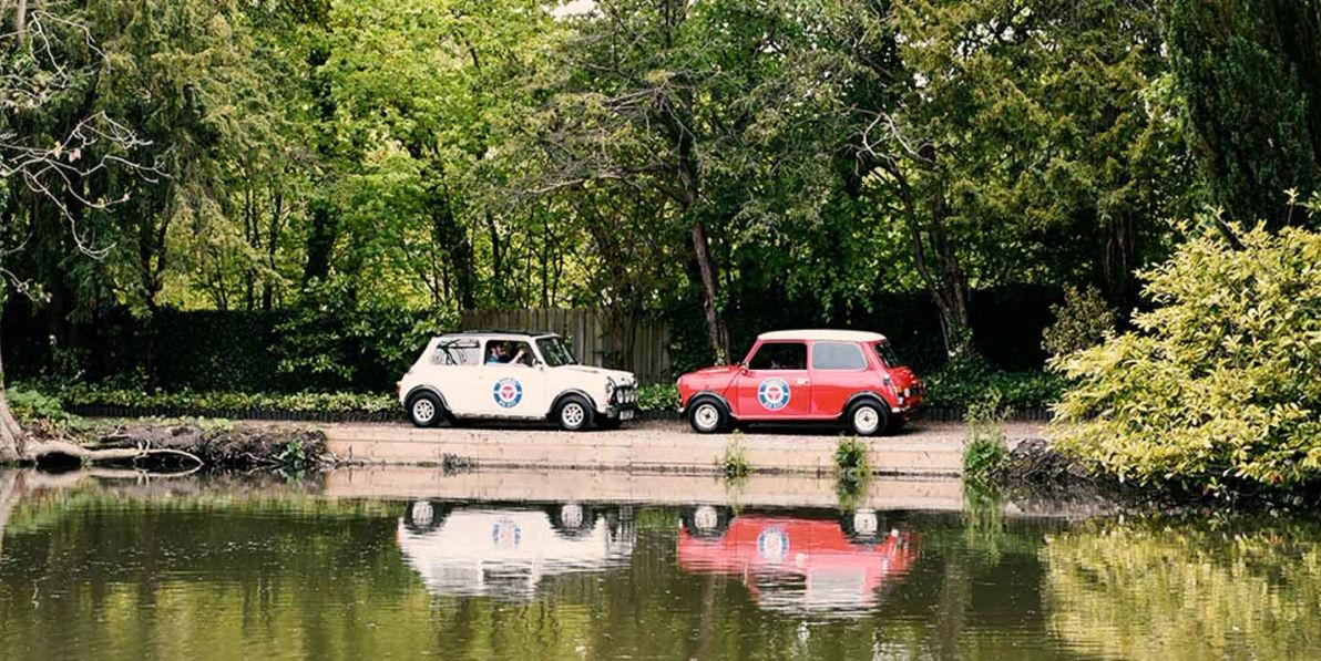 Two small cars parked next to a body of water.