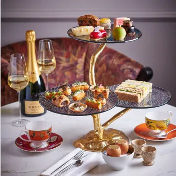 A three-tiered tray of food and champagne on a table.