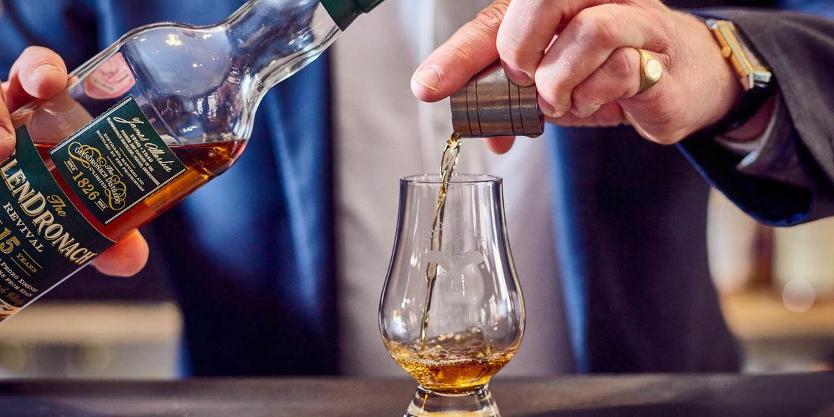 A man pouring whisjy into a glass.