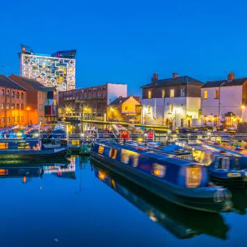 Boats docked in a canal near buildings at dusk.