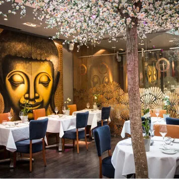 A restaurant with a large buddha head on the wall.