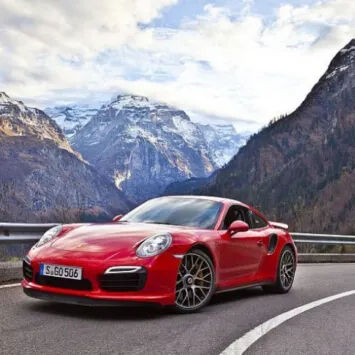 The red Porsche 911 GTS is driving down a mountain road.