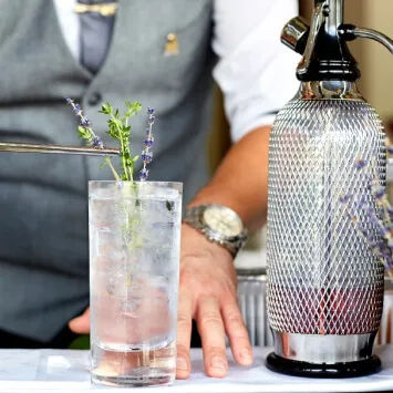 A bartender pouring a drink into a glass.