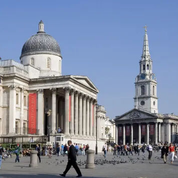 A group of people walking around a square in front of a building.