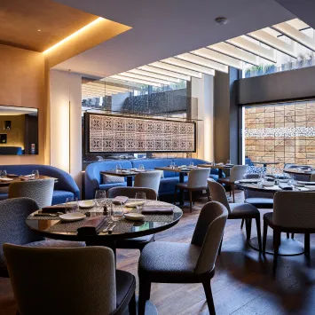 The interior of a restaurant with blue chairs and tables.