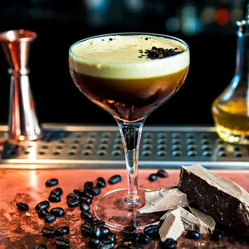 A cocktail with chocolate and coffee beans on a bar