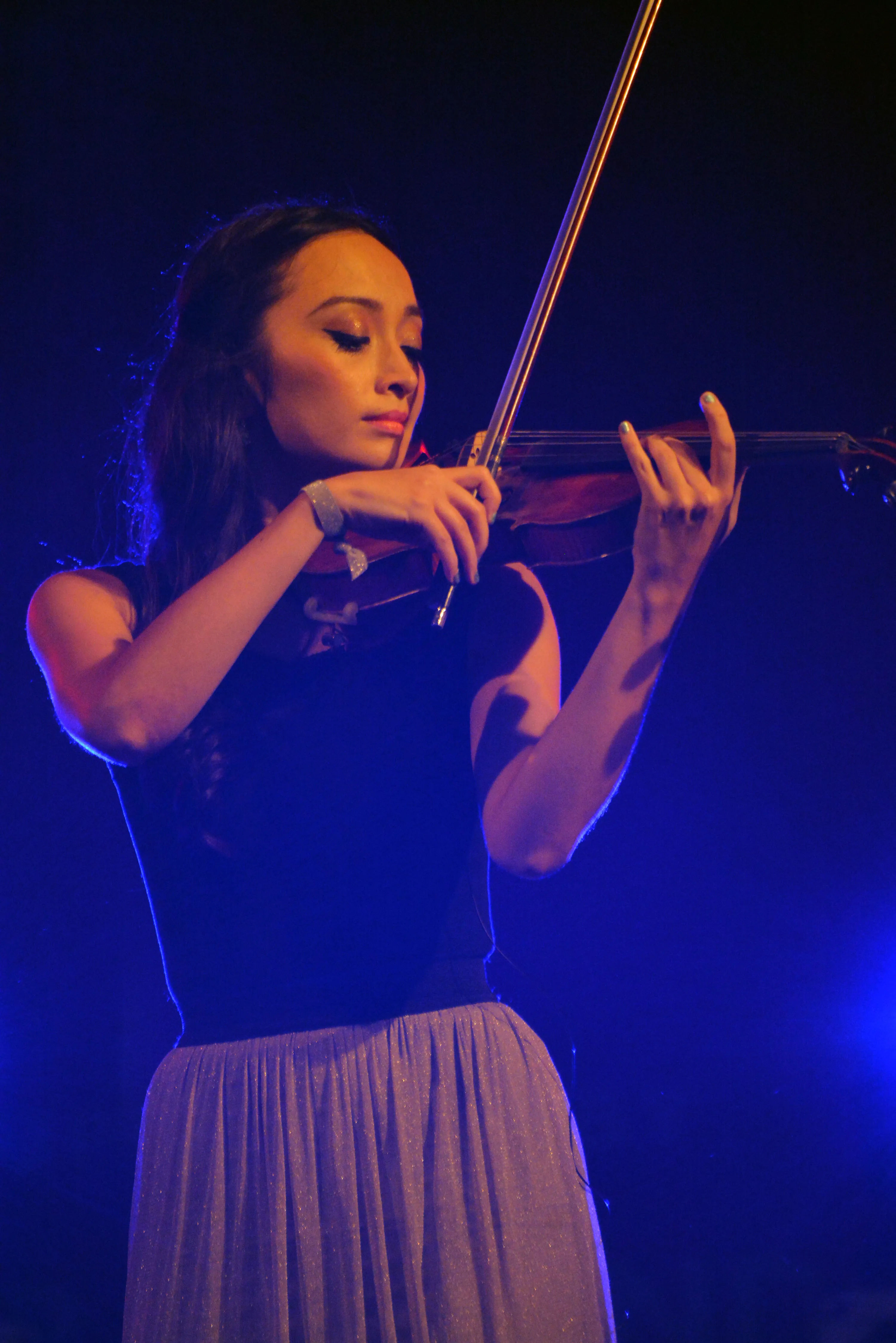 A young woman playing the violin on stage.