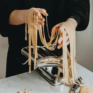 A woman is making pasta with a pasta machine