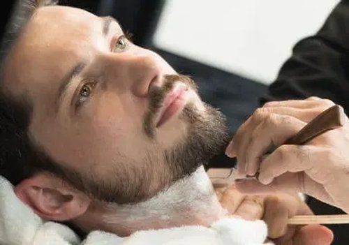 A man getting his beard shaved by a barber.