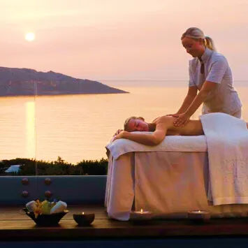 A woman getting a massage on a deck overlooking the ocean.