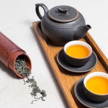 Two cups of tea on a tray with a wooden spoon.