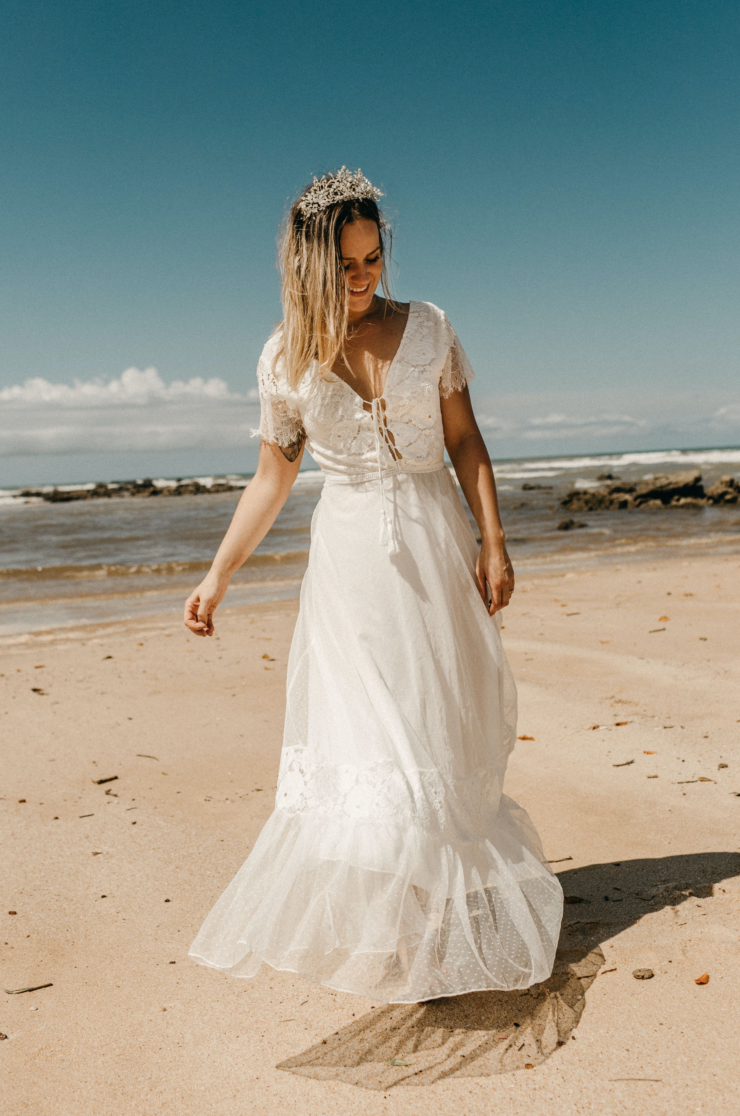 A woman in a white wedding dress walking on the beach.