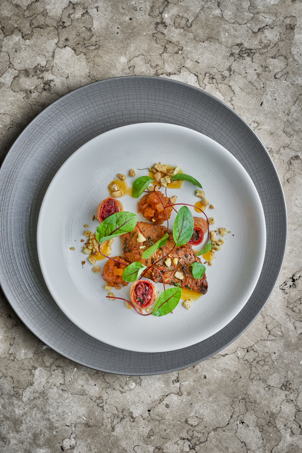 A white plate with tomatoes and basil on it.