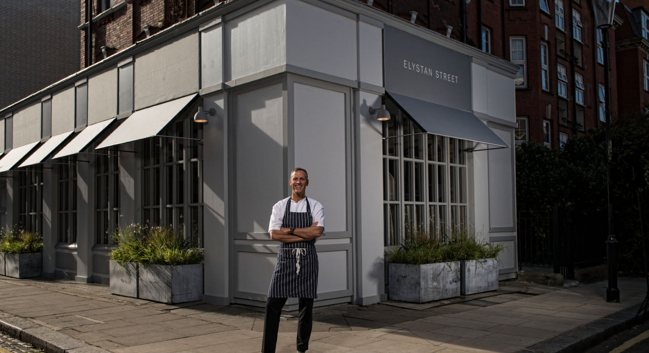 A chef standing in front of a restaurant